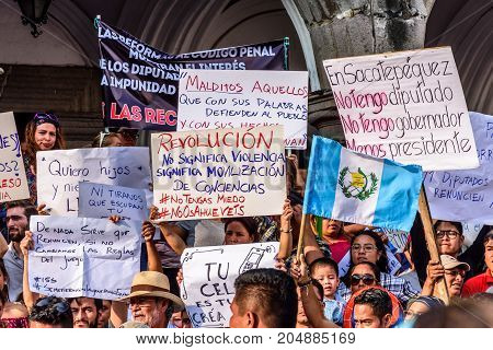 Antigua Guatemala - September 15 2017: Locals wave Guatemalan flags & slogans protesting against government corruption in front of city hall on Guatemala's Independence Day.