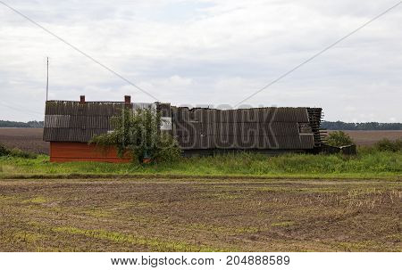 The Old Farm House, Part Of The Extension Which Began To Collapse. The Gray Sky With Rainy Weather. 