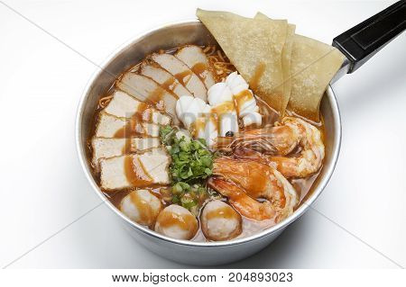 Pot of spicy instant noodles with red sauce isolated on white background. Topping with fried dumplings seafood shrimp squid tofu slide pork ball and coriander