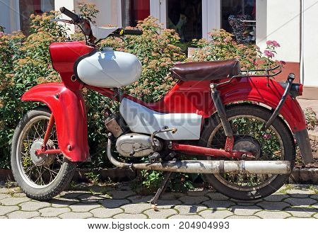 Old red motorbike on the street in summer