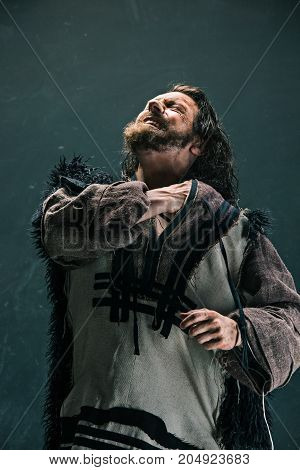 Actor in makeup, a poor man on black studio background. The bum in canvas rags. concept of vagrancy and survival