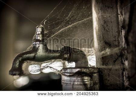 A tap covered with spider web no more water.