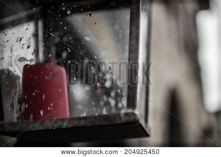 A lantern holds a red candle turned off.