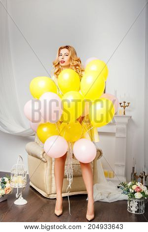 Happy smiling woman is looking on an air colorful balloons having fun.