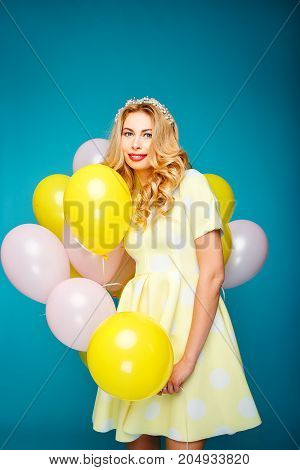 Happy smiling woman is looking on an air colorful balloons having fun.