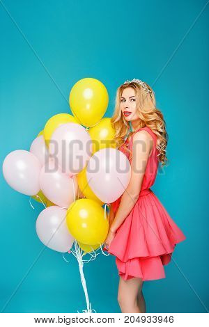 Happy smiling woman is looking on an air colorful balloons having fun.
