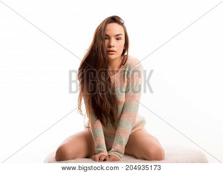 Sexy girl woman poses on sofa on white background in studio in sweater pullover