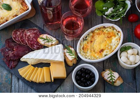 Board with basturma, salami, camembert, cheese, other delicacies and pink wine. Top view