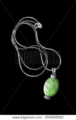 Vintage green nephrite pendant with diamonds on a chain isolated over black