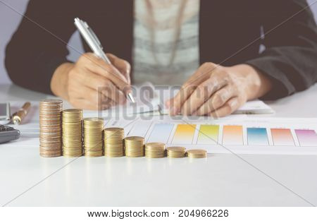 Businessman writing and analyzing for business with stack coins on the table. Financial analyzing and success concept.