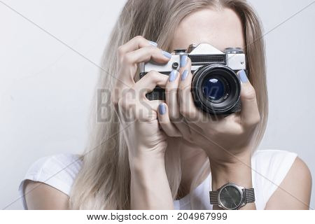 Young beautiful woman taking a photo with a retro camera Toned
