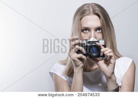 Young beautiful woman taking a photo with a retro camera Toned