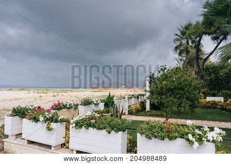 Coastline resort area Golem with a sandy beach and flower beds with green grass.