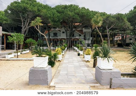 ALBANIA GOLEM- September 20 2015: The road through a sandy beach to a guest two-storey house surrounded by green trees in the resort of Golem.
