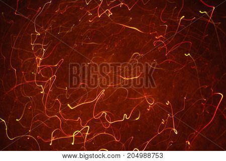 Abstract background of colorful crankles in motion on black. Bokeh of defocused curves, blurred neon orange leds, similar to gas discharge plasma ball, tesla sphere