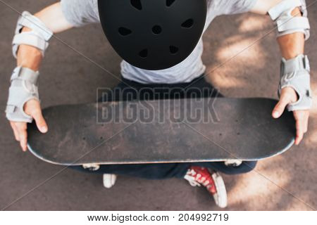 Skateboard halmet, elbow and gloves protection on unrecognizable skateboarder. Extreme sport challenge and training, motivation for win in competition