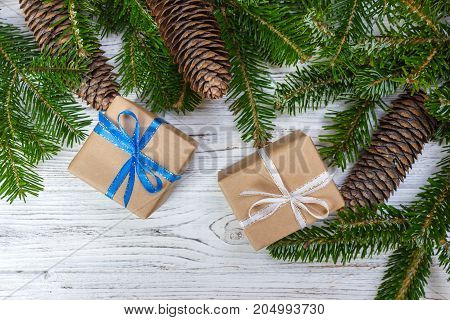 Christmas gift box on the white wooden table backgroundspruce branchpine conesframetop view space for text.