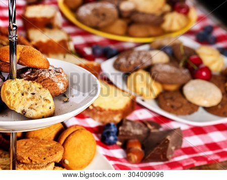Cookies and sand biscuit on tier cake stand with blueberry chocolate on kitchen on picnic table in rustic natural style. Composition of confectionery.