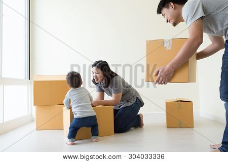 Family Unpacking Boxes In New Home On Moving Day, Happy Father Mother And Son Is Having Fun With Car