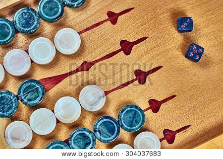 Backgammon Game. Game Dice Made Of Stone Lie On The Backgammon Board Against The Background Of Check