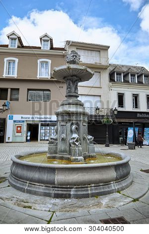 Lourdes, France - June 18, 2018: Place Marcadal. Old Fountain With Stone Fishes On The Background Of