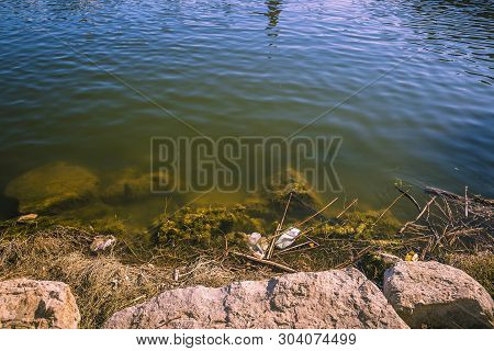 Polluted Water With Plastic Waster In The Riverbank