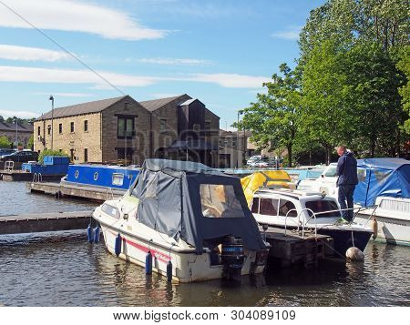 Brighouse, West Yorkshire, United Kingdom: 24 May 2017: A Man On A Houseboat Surrounded By Barges Mo