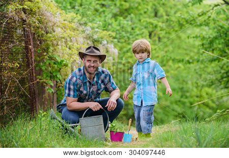 Planting Flowers. Growing Plants. Take Care Of Plants. Boy And Father In Nature With Watering Can. G