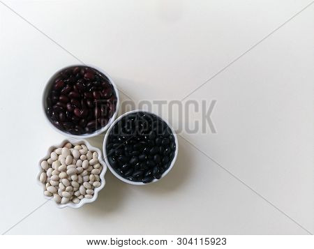 Layout Three Bowls Of White, Red And Black Beans On A White Background. Top View.