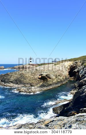 Isla Pancha, Ribadeo, Spain. Island With Two Lighthouses And Violet Flowers. View From A Cliff, Sunn