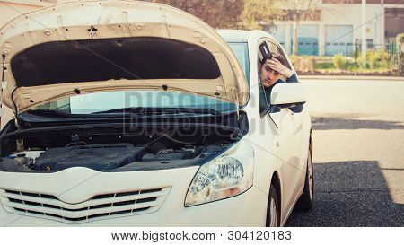 Stressed Driver Behind Steering Wheel Looking Out Of Window At The Car Engine, Hand To Forehead Gest