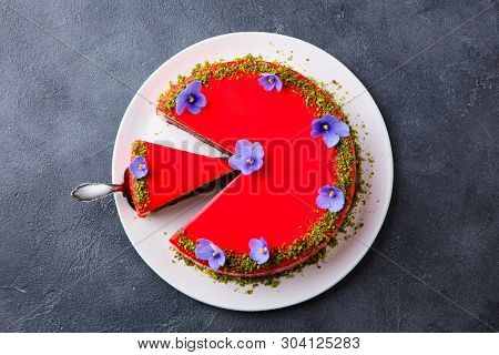 Raspberry Layerd Cake Decorated With Violet Flowers On White Plate. Grey Stone Background. Top View
