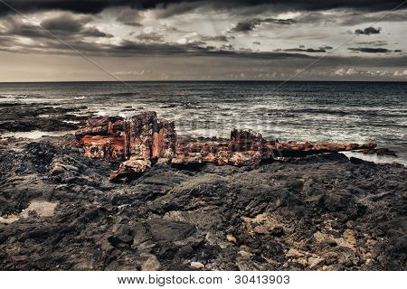 schipbreuk op een lava strand tijdens storm