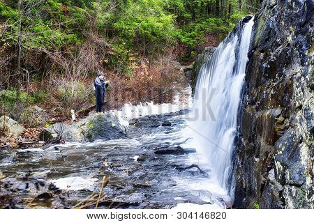 A Chinese Man Taking Pictures Of A Flowing Waterfall At Burr Pond State Park In Torrington Connectic