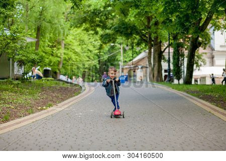 Little Boy Riding Scooter In City Park In Aummer. Kids Sports Outdoors. Happy Child Playing With His