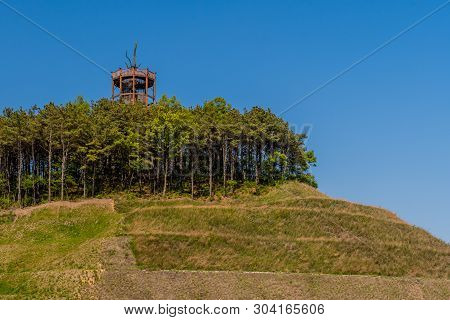 Wooden Observation Tower In Center Of Grove Of Trees On Top Of Manicured Hill.