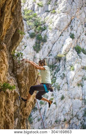 Rock Climbing And Mountaineering In The Paklenica National Park. A Woman Overcomes A Challenging Cli