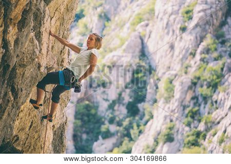 Rock Climbing And Mountaineering In The Paklenica National Park. A Woman Overcomes A Challenging Cli