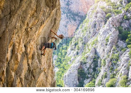 Rock Climbing And Mountaineering In The Paklenica National Park. A Woman Overcomes A Challenging Cli