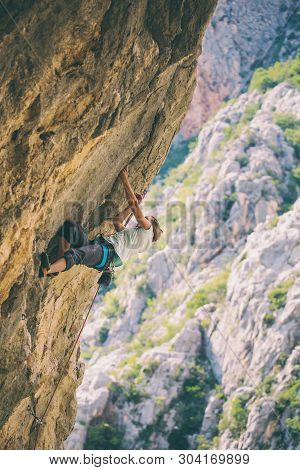 Rock Climbing And Mountaineering In The Paklenica National Park. A Woman Overcomes A Challenging Cli