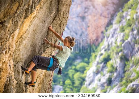 Rock Climbing And Mountaineering In The Paklenica National Park. A Woman Overcomes A Challenging Cli
