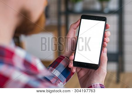 Mockup Image: Man Looking At Black Smartphone With White Blank Screen. Close Up View Of Man Hands Wi