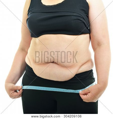 Overweight unhappy young woman measuring her hips, isolated over white background. Overeating xxl size woman with measuring tape