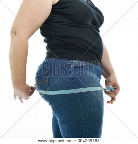 Overweight unhappy young woman measuring her hips, isolated over white background. Overeating xxl size woman with measuring tape