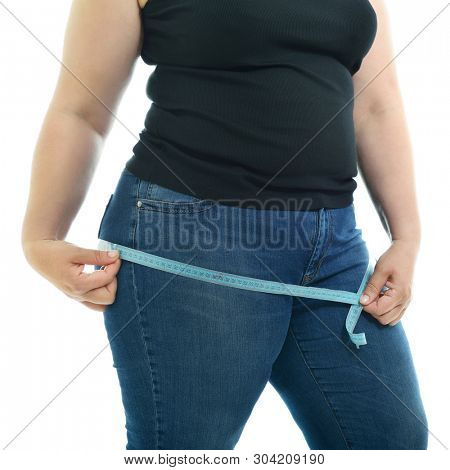 Overweight unhappy young woman measuring her hips, isolated over white background. Overeating xxl size woman with measuring tape