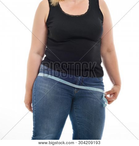 Overweight unhappy young woman measuring her hips, isolated over white background. Overeating xxl size woman with measuring tape
