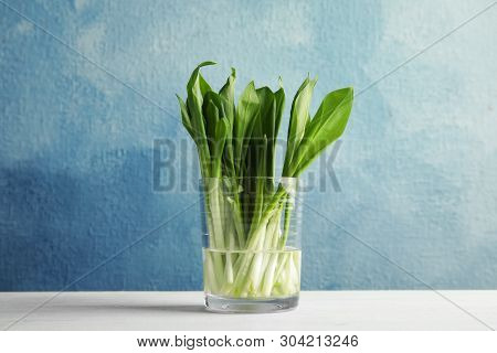 Glass Of Wild Garlic Or Ramson On Table Against Color Background