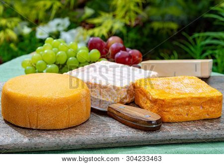 French Cheeses Collection, Yellow  Le Peche Des Bons Peres Cheese Served With Grapes On Marble Plate