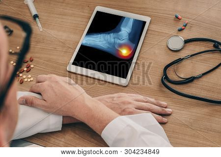 Doctor Watching A Digital Tablet With X-ray Of The Foot With Pain In The Heel