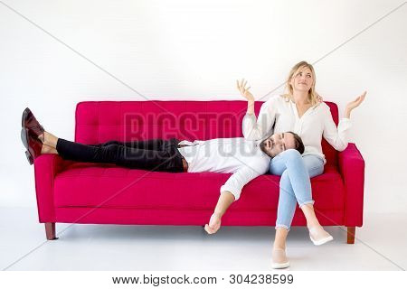 Couple In Love Boyfriend Lying Down Or Sleep On Her Knee Or Leg Girlfriend On  Red Sofa At Home On W